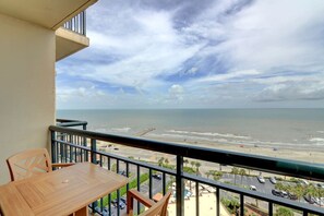 A balcony with a view of the beach and ocean.
