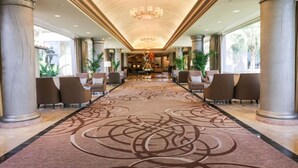 A spacious lobby with a patterned carpet, large columns, and a chandelier. - Gorgeous San Luis Condo! Amazing Pool & Amenities (Galveston)