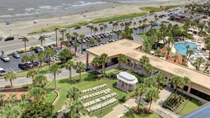 A resort with a pool, beach access, and a parking lot with palm trees. - Gorgeous San Luis Condo! Amazing Pool & Amenities (Galveston)
