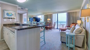 A hotel room with a kitchen area, dining space, and a seating area with a view of the ocean. - Gorgeous San Luis Condo! Amazing Pool & Amenities (Galveston)