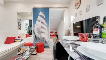 A modern dining area with a large table set for a meal, a red sofa, and a wall-mounted clock.