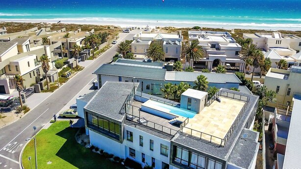 A modern building with a rooftop pool, surrounded by a coastal neighborhood with a beach view. - Villa Sunset Mansion Cape Town (Cape Town)