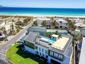 A modern building with a rooftop pool, surrounded by a coastal neighborhood with a beach view.