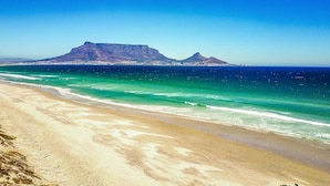 A beach with clear turquoise waters and a mountain in the background. - Villa Sunset Mansion Cape Town (Cape Town)