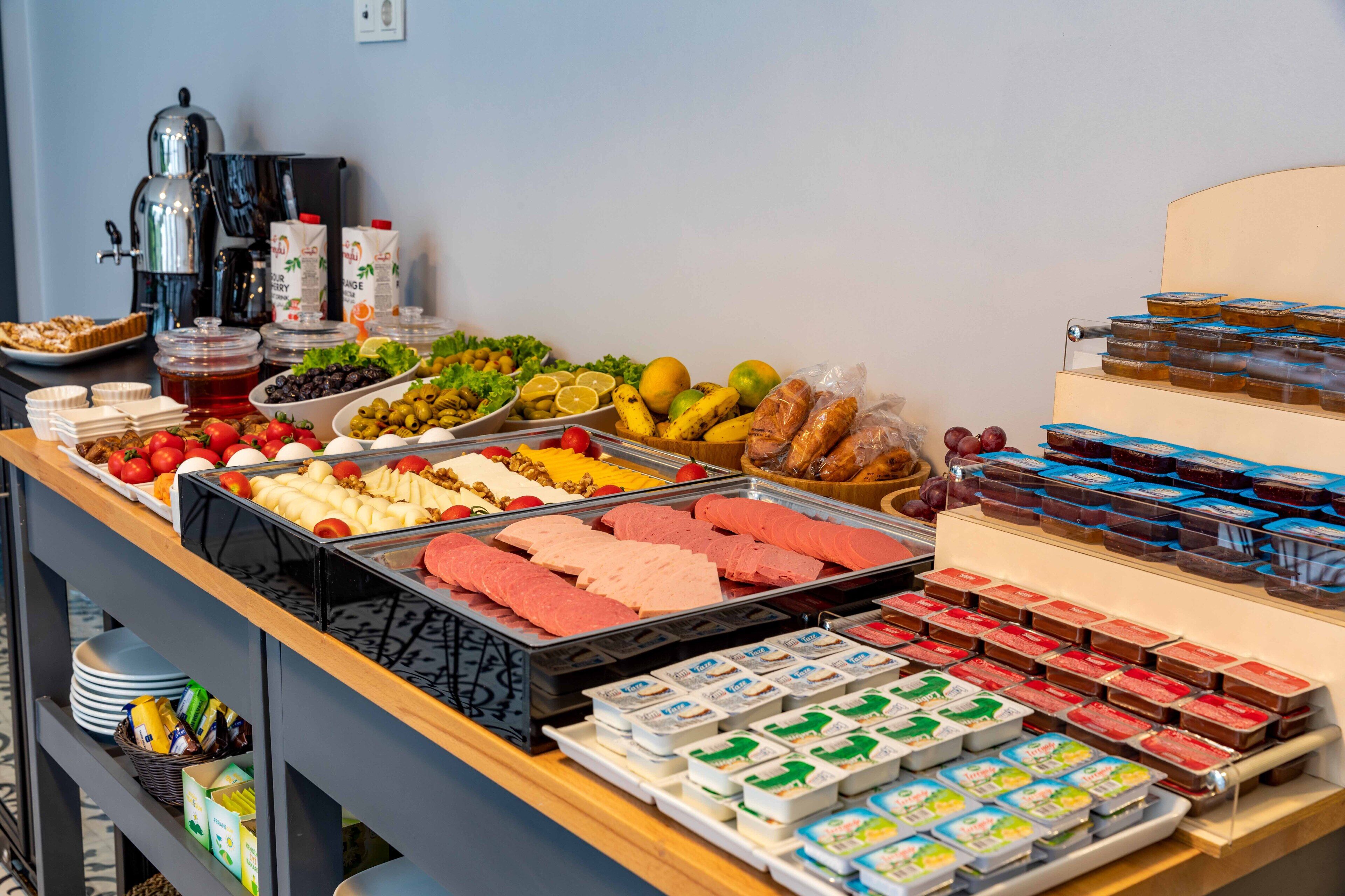 Un bufé con diferentes opciones de comida, incluyendo frutas, carnes y postres.