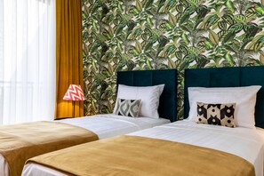 A hotel room with two beds, a tropical leaf-patterned wallpaper, and a lamp with a chevron design. - Green Parrot Hotel (Istanbul)