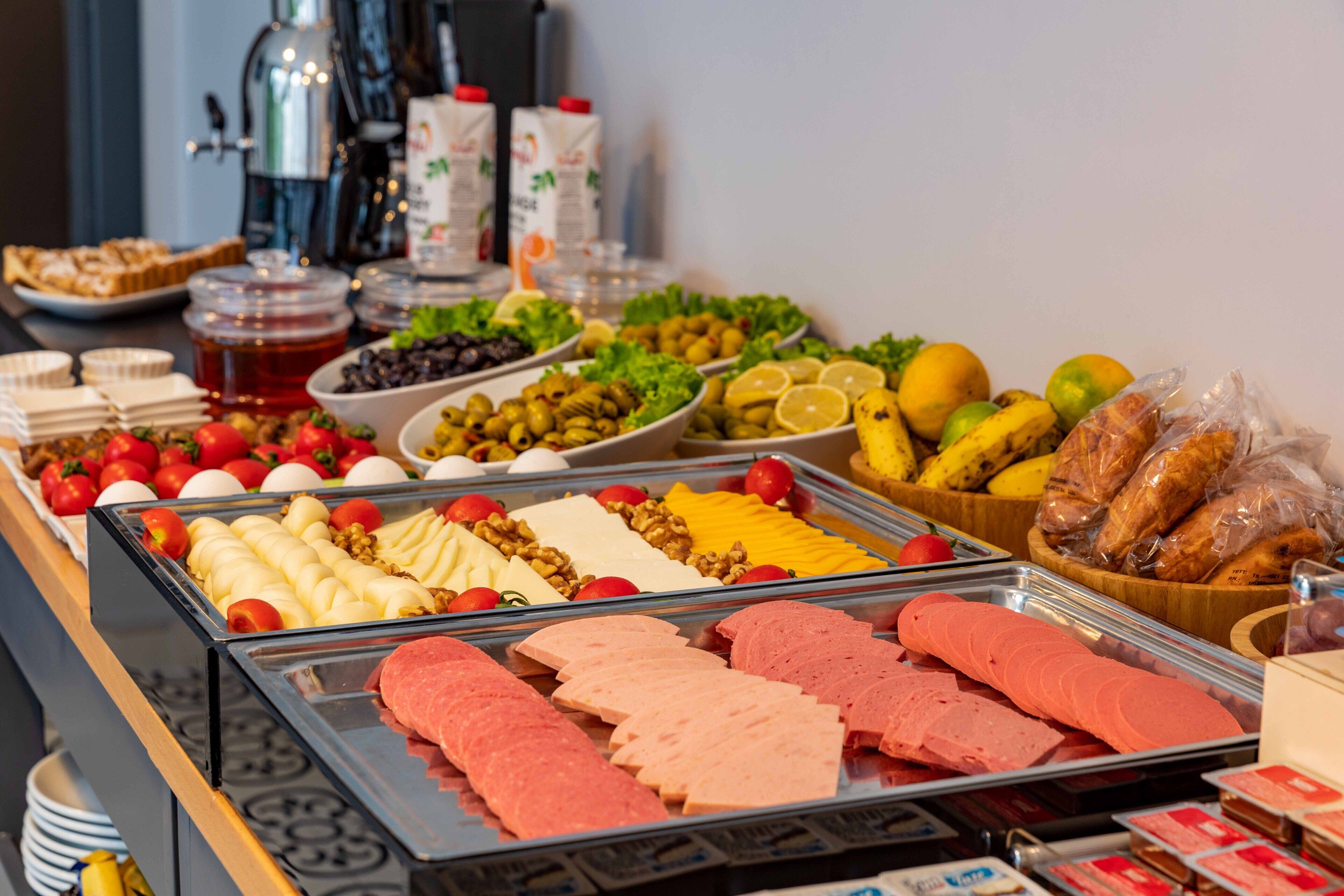 Ein reichhaltiges Buffet mit verschiedenen Speisen, darunter Fleisch, Käse, Obst und Gemüse.