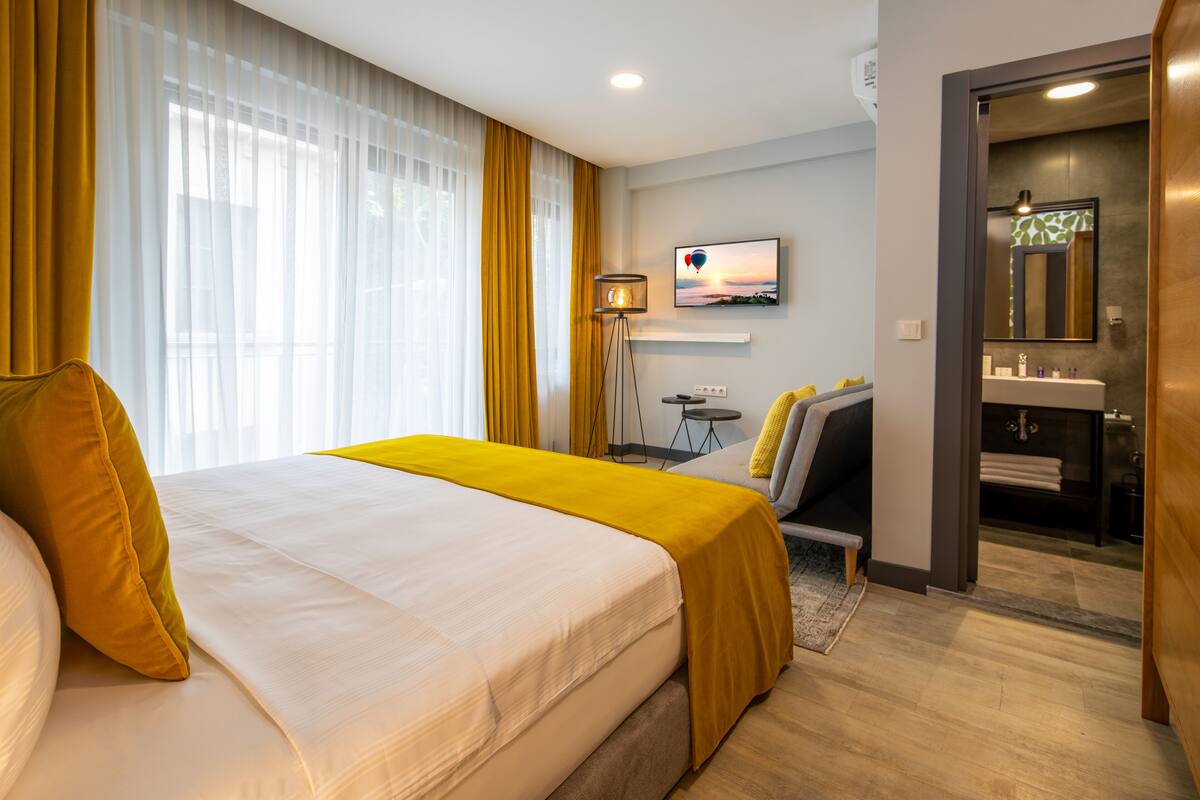 A hotel room with a large bed, a desk, a chair, a TV, and a bathroom.