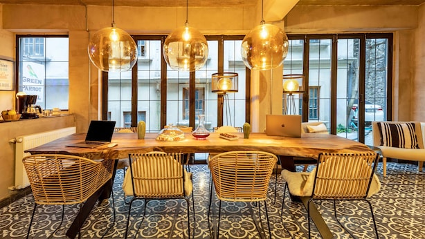 A modern dining area with a large wooden table, wicker chairs, and pendant lights. - Green Parrot Hotel (Istanbul)