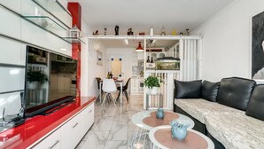 Une cuisine moderne avec un plan de travail rouge, des armoires blanches et un coin repas comprenant une table et des chaises blanches.