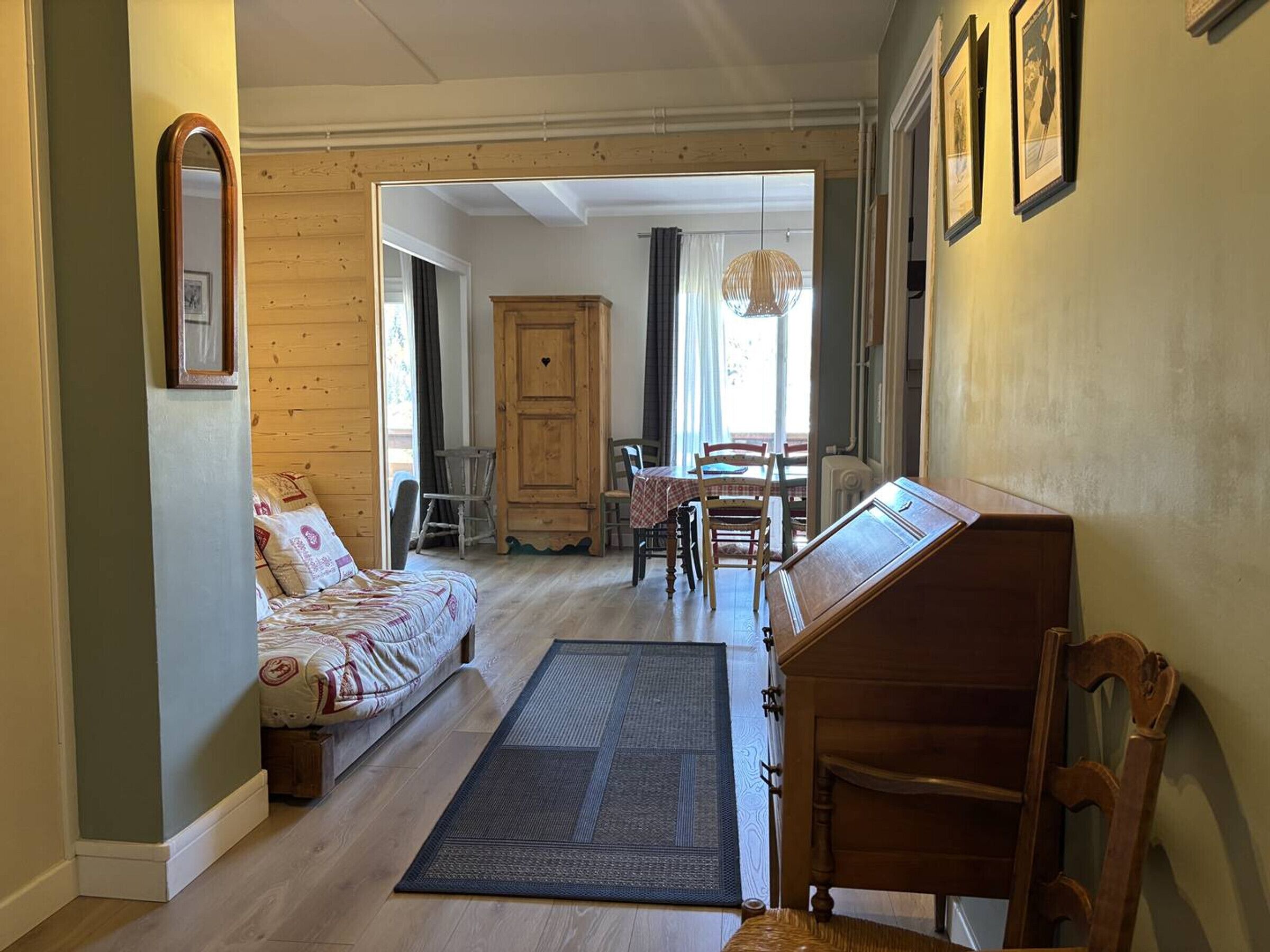 Ein gemütliches Zimmer mit einem Bett, einem Holztisch und einem Esstisch mit Stühlen.