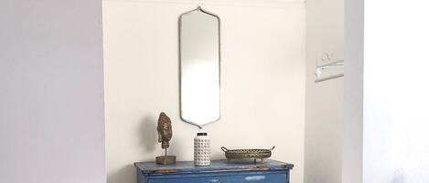 A room with a blue dresser, a mirror, and a hanging light fixture.