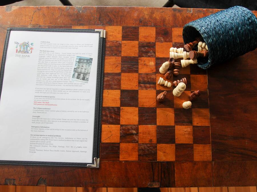 A wooden table with a chessboard and a document titled "The Bank" on it.