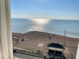 Una playa con un paseo marítimo empedrado y un pequeño edificio, presumiblemente una estación de salvavidas, con vista al mar.