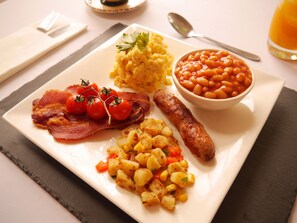 A breakfast plate with bacon, sausages, potatoes, beans, and scrambled eggs. - The Bank Hotel & Bistro (St Leonards-On-Sea)