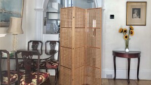 A dining area with a wooden partition, a table with chairs, a vase with sunflowers, and a framed picture on the wall. - Entire Cottage Style Flat in Heart of Wallingford (Wallingford)