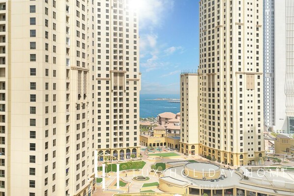 A high-rise building complex with multiple floors, a central courtyard, and a view of the sea. - LUX Contemporary Suite Marina View 6 (Dubai)