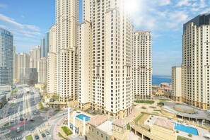 A high-rise residential building with multiple floors, a swimming pool, and a landscaped area. - LUX Contemporary Suite Marina View 6 (Dubai)