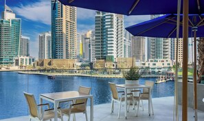 An outdoor seating area with a view of a city skyline and a body of water.