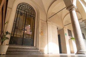 A grand entrance with a large arched doorway, a potted plant, and a staircase leading to the entrance. - The Best Rent - Cozy apartment in Milan downtown (Milan)