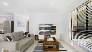 A modern living room with a sofa, coffee table, and a large TV.