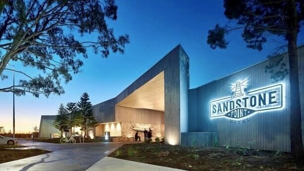 A modern hotel with a prominent sign reading "SANDSTONE POINT HOTEL".
