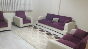 Una sala de estar con un sofá, dos sillones y un tapiz estampado.