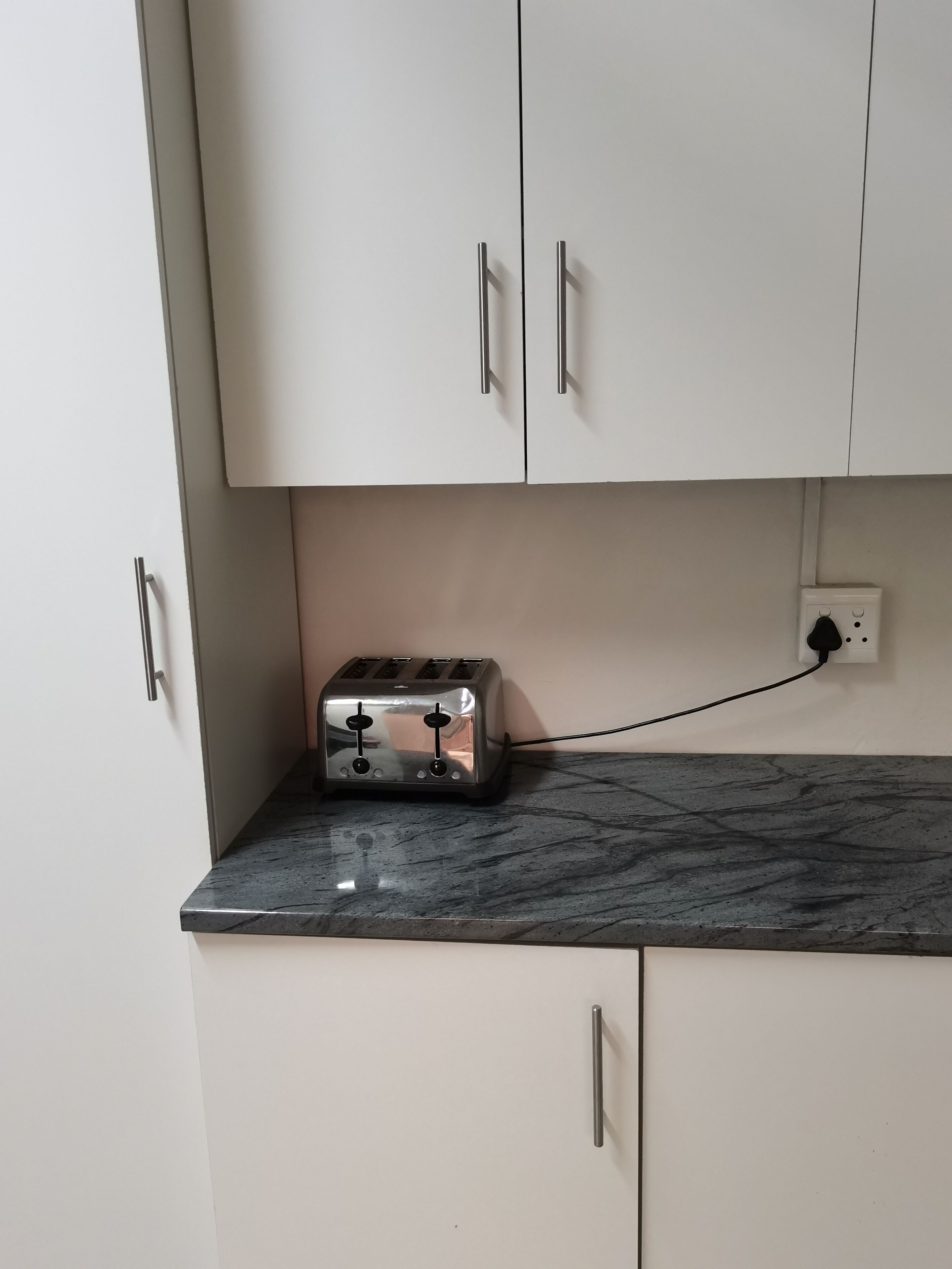 Una cocina con un tostador sobre una encimera de mármol, conectado a un enchufe.