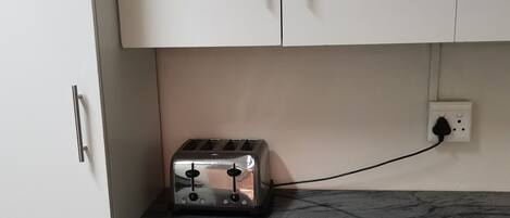 Una cocina con un tostador sobre una encimera de mármol, conectado a un enchufe.