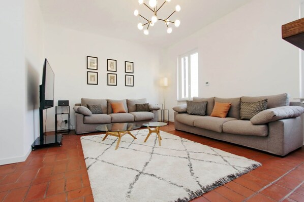 Ein Wohnzimmer mit zwei Sofas, einem Couchtisch, einem Fernseher und gerahmten Bildern an der Wand.