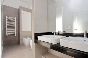 Ein modernes Badezimmer mit zwei Waschbecken, einem Bidet und einem Handtuchhalter.
