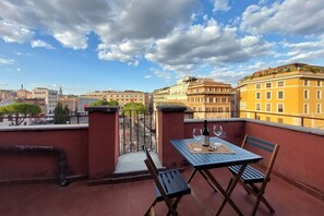 Ein Balkon mit Tisch, Stühlen und einer Weinflasche.