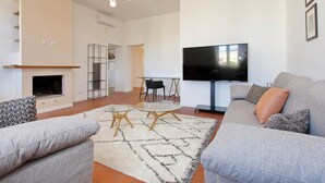Ett modernt vardagsrum med en öppen spis, soffa, TV och en matplats.