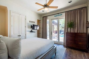 A bedroom with a bed, a ceiling fan, a TV, a plant, and a sliding glass door leading to an outdoor area. - Private Pool-4 bikes-Private Beach Access (Santa Rosa Beach)