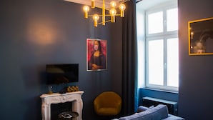Ett modernt vardagsrum med en öppen spis, en soffa, en gul fåtölj och ett stort fönster med gardiner.