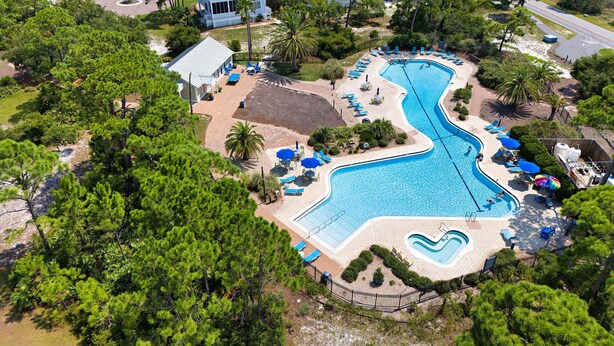 A resort with a large swimming pool, multiple guest villas, and lush greenery. - Heated Pool, 4 BR,  Island Blessing, Beach Chairs, Short Walk to Beach (St. George Island)