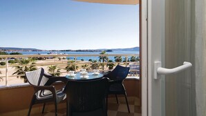 En balkon med et bord og stole, der ud til en strand og havet.