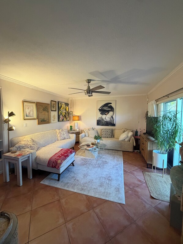 Un salon avec un canapé, une table basse et un ventilateur de plafond.