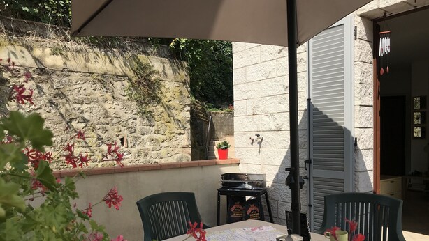 Patio esterno con tavolo apparecchiato per due, una mappa, una caffettiera e una pasticceria.