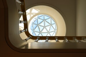 A spiral staircase with a circular window at the top, allowing natural light to enter.