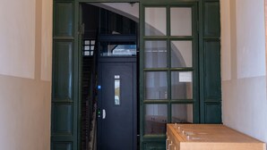 A hallway with a wooden door, a staircase, and a wooden cabinet. - Giuditta in Trastevere (Rome)