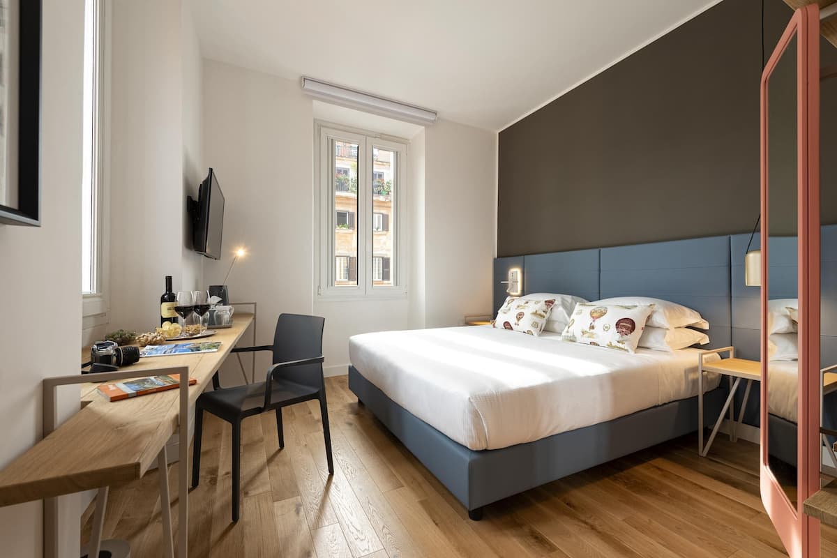 A modern bedroom with a large bed, a desk, and a TV.