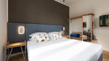 Una habitación de hotel moderna con una cama grande, mesitas de noche, un escritorio y un espejo.