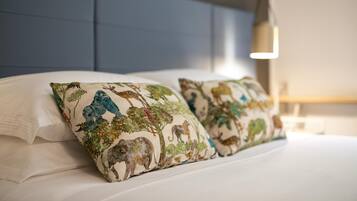 A bed with white bedding and decorative pillows featuring animal prints.
