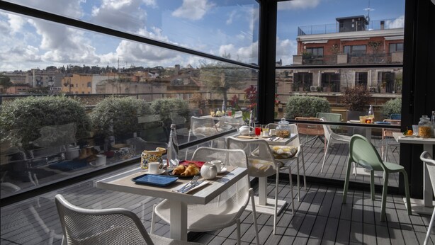 A terrace with outdoor seating, a table set with breakfast items, and a view of the cityscape. - Giuditta in Trastevere (Rome)