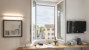 A room with a desk by a window, a mounted TV, and a framed picture on the wall. - Giuditta in Trastevere (Rome)
