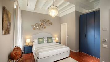 Una camera da letto con un letto grande, un lampadario, un armadio blu e un quadro appeso al muro.