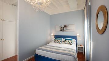 Un dormitorio con cama, candelabro, espejo en la pared y una puerta.