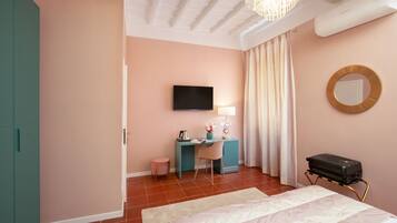 A bedroom with a bed, a desk, a chair, a television, a mirror, and a suitcase.