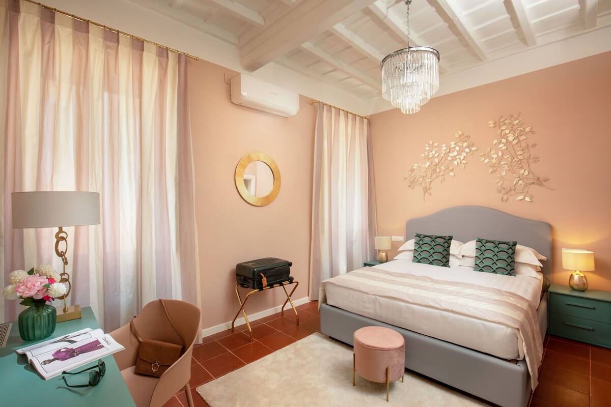 A bedroom with a bed, a desk, a chair, a small table, and a decorative wall piece.